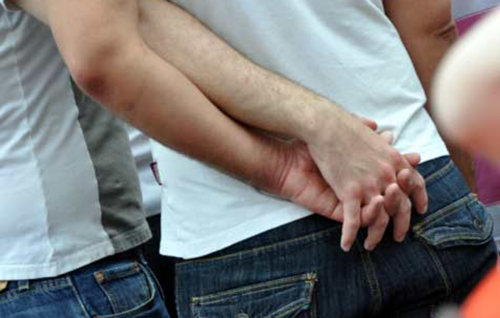 Gay Couple Holds Hands behind back